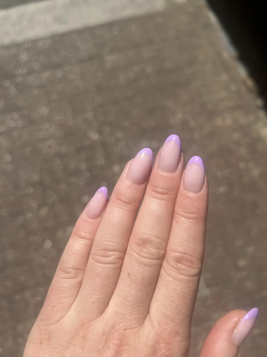 Long almond nails in a soft lilac-to-pink ombre, photographed over paving