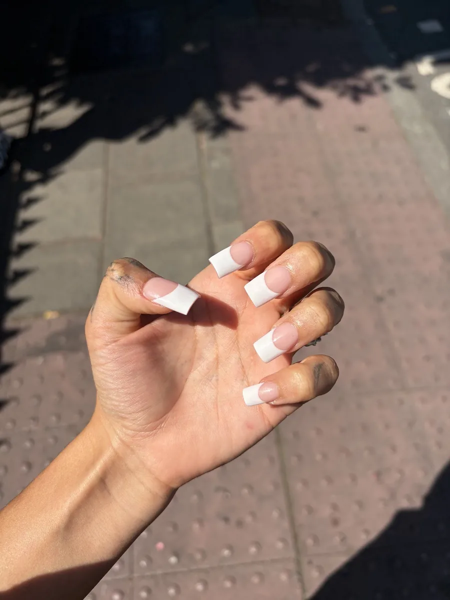 Long square white French tips photographed on a sunlit pavement